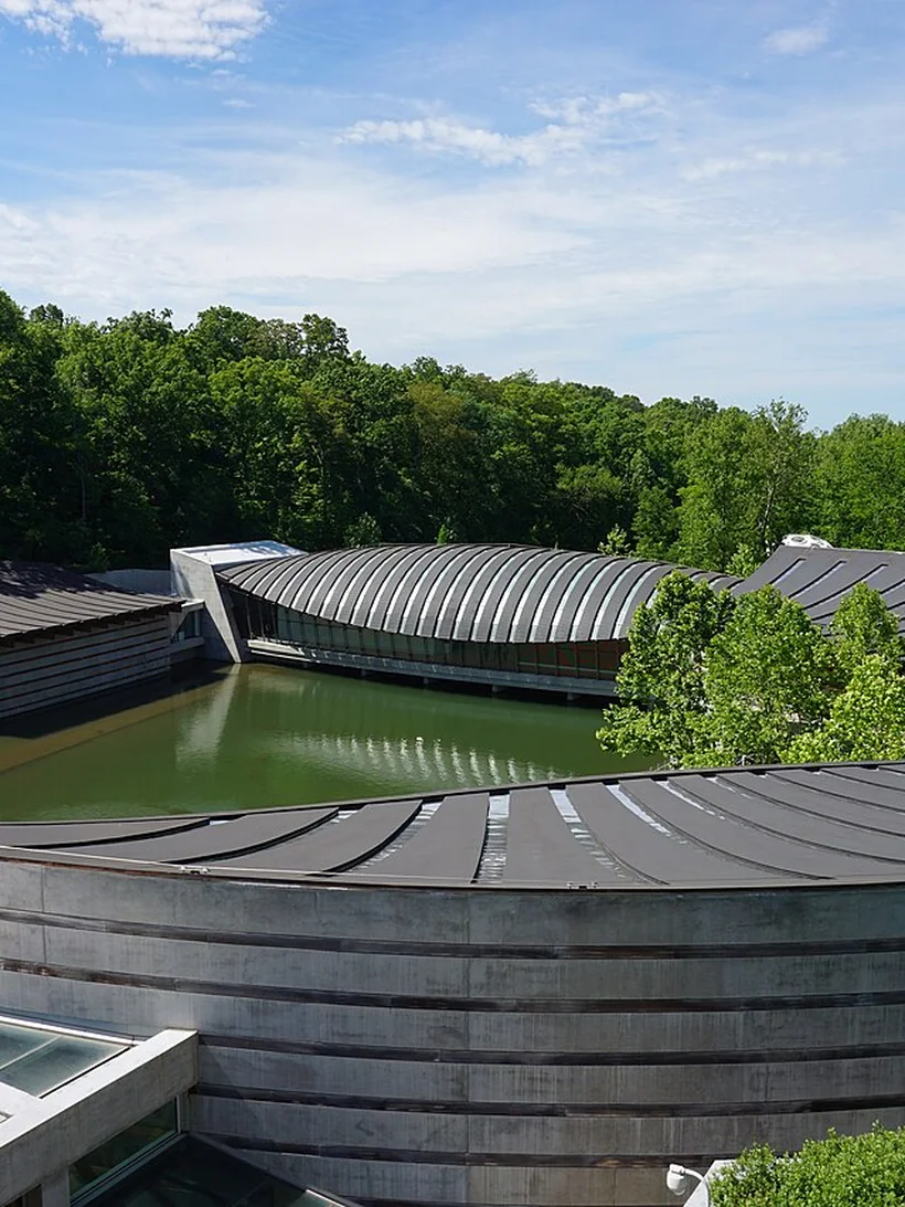 The copper and timber pavilions of Crystal Bridges Museum arching over a spring-fed pond