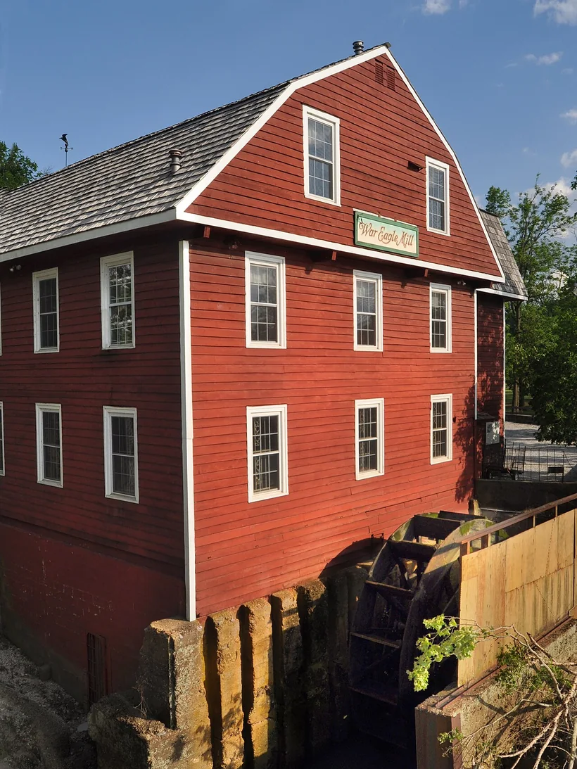 The red siding and water wheel of War Eagle Mill beside the War Eagle River